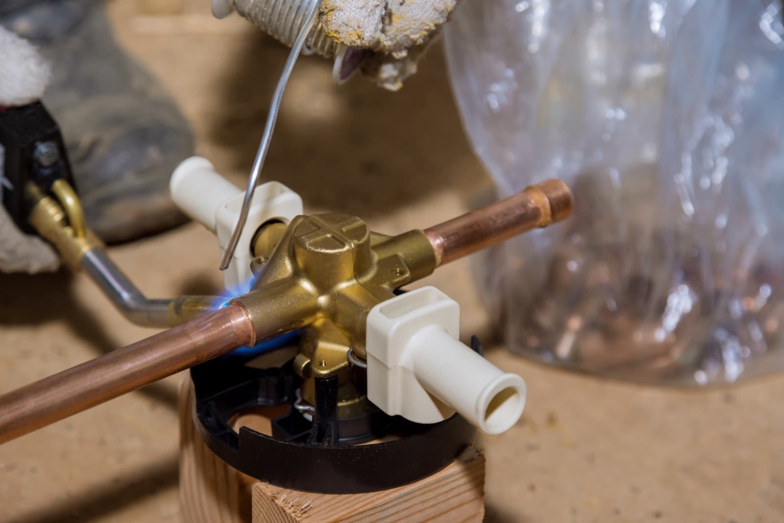 Plumber soldering copper pipe with a torch during a repair in a Coppell home