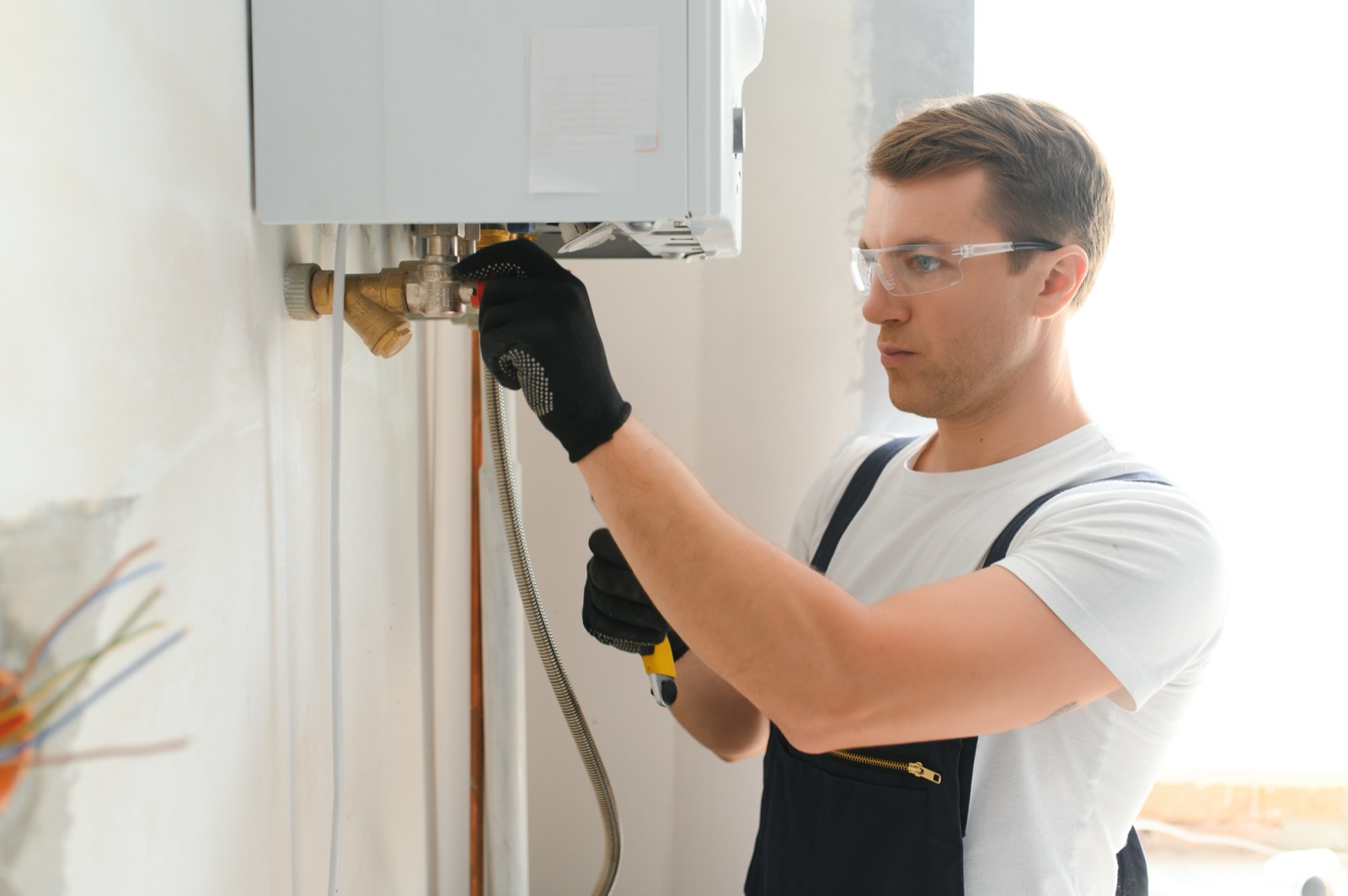 Licensed plumber working on a water heater, backed by written workmanship warranty terms